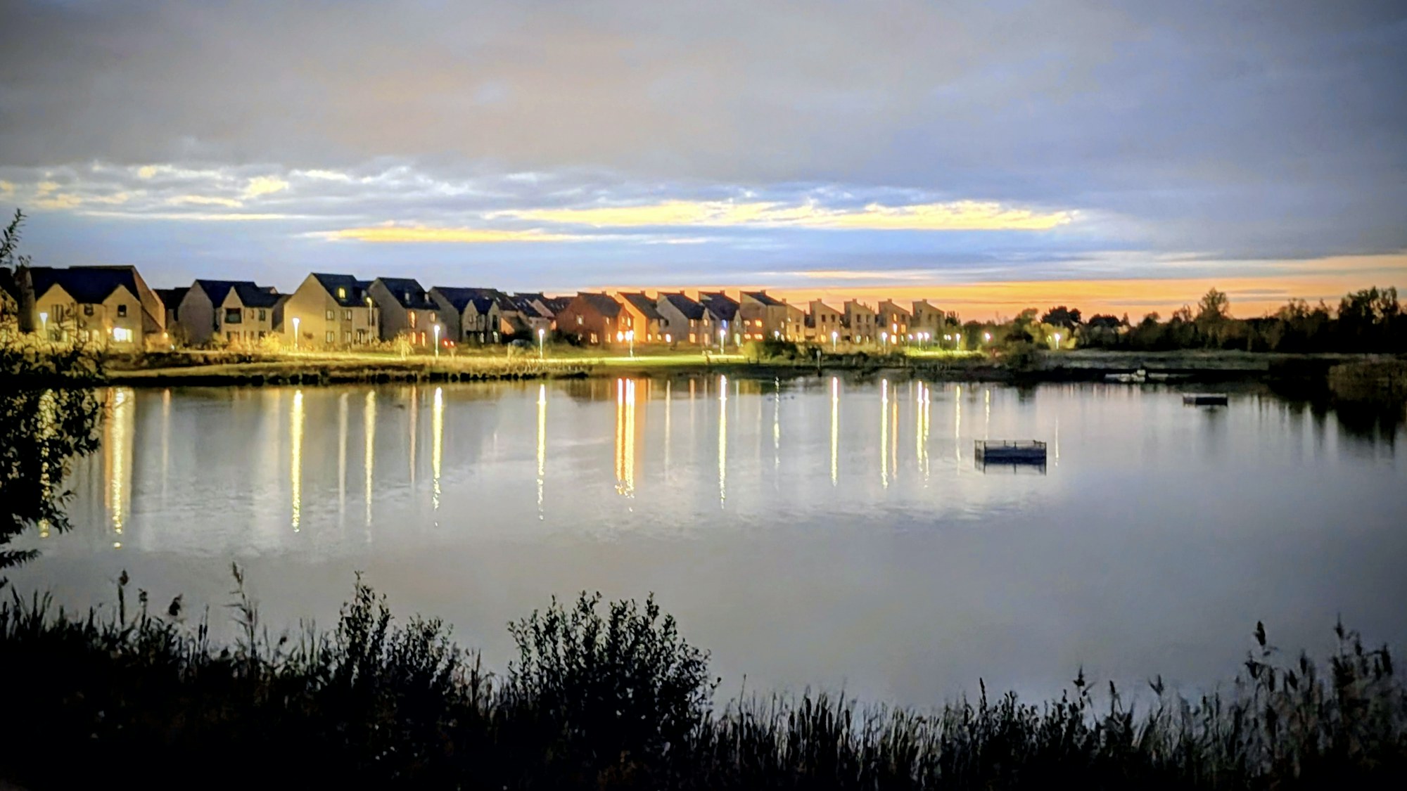Community lake at dusk with homes along the shoreline